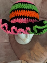 a crocheted hat with pink, green, and black stripes