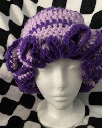 a purple and white crocheted hat on a mannequin