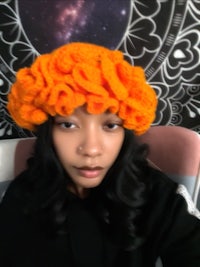 a woman wearing an orange crocheted hat